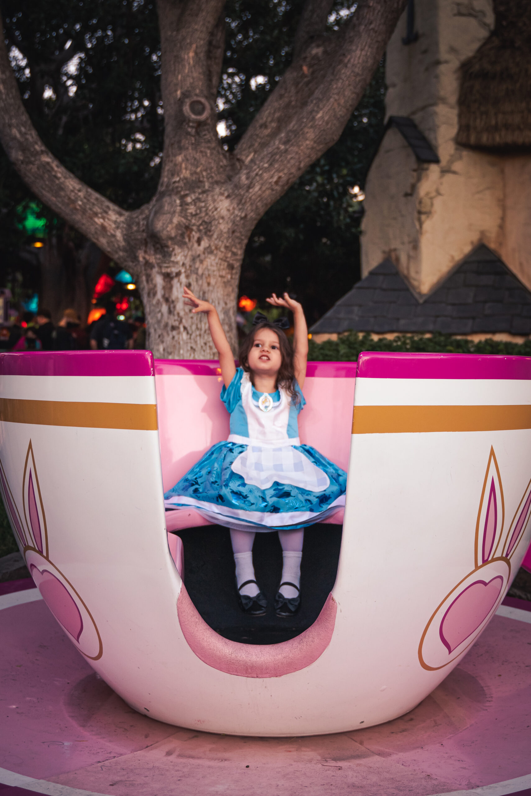 A child dressed as Alice in Wonderland dances while sitting in a teacup in Fantasyland at Disneyland in Anaheim, California